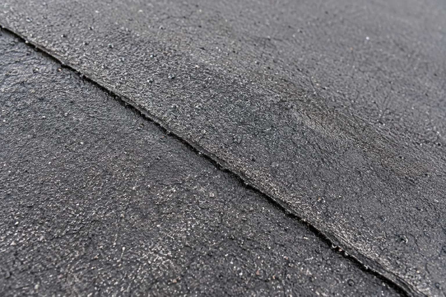 Close view of an overlapping dark membrane seam with rain droplets