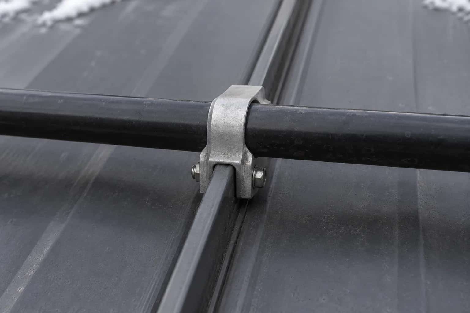 Metal rail attached with a clamp at a raised seam on a grey metal roof