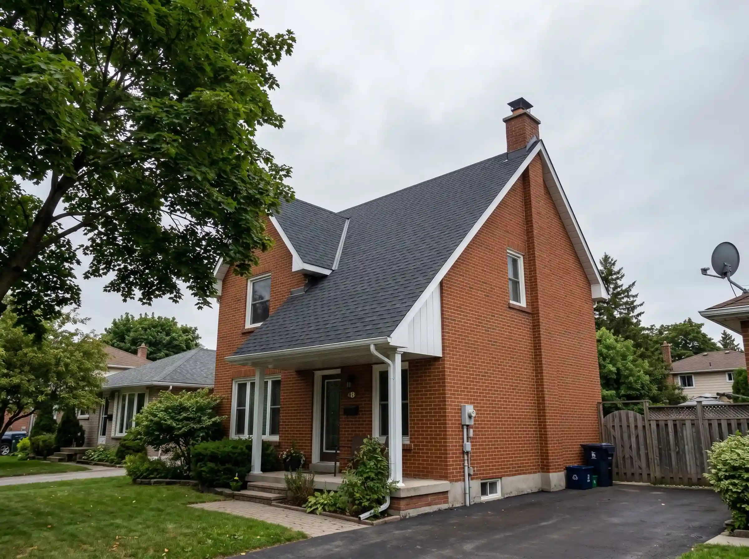Brick house with intersecting shingle roof slopes, a porch and a paved driveway